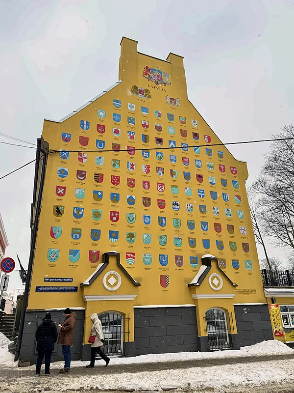 A yellow building covered in coats of arms